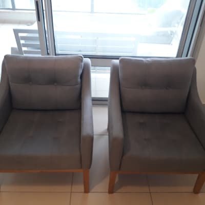 שני כורסאות אפורות עם רגלי עץ על רצפה בהירה