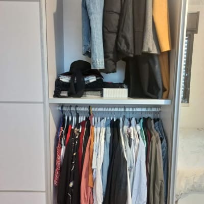 ארון בגדים מאורגן עם בגדים תלויים ומגירות מסודרות