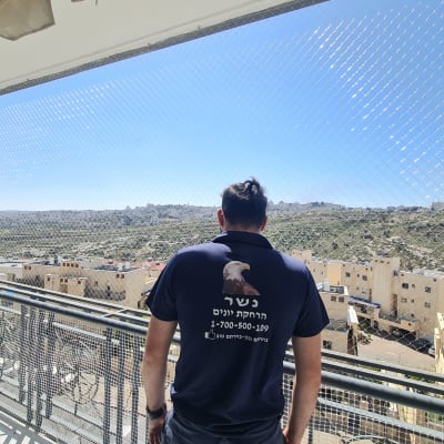 אדם עומד מול רשת למניעת כניסת יונים במרפסת