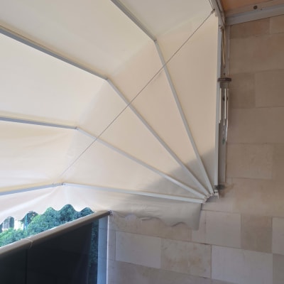 סוכך לבן עם מסגרת מתכת על קיר אבן