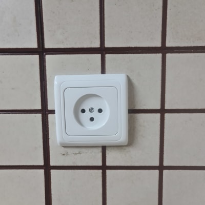 שקע חשמלי לבן מותקן על קיר מרוצף