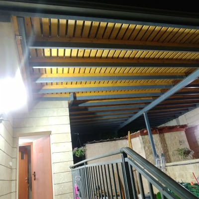 פרגולה מעץ ומתכת מעל שביל מרוצף