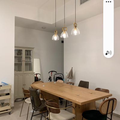 שלושה מנורות תלויות מהתקרה מעל שולחן עץ