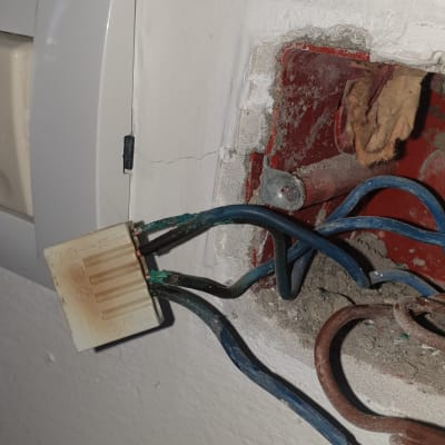 חוטי חשמל חשופים בקיר עם חיבור פלסטיק