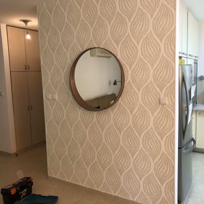 קיר עם טפט דוגמת עלים ומראה עגולה