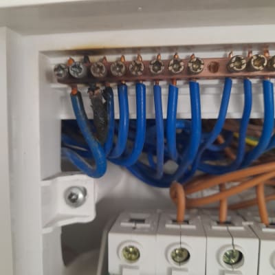 חוטי חשמל כחולים מחוברים ללוח חשמל עם ברגים