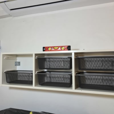 מדף עם סלסלות שחורות ומפלס בנאים אדום