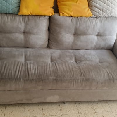 ספה אפורה עם כריות צבעוניות על רצפת אריחים