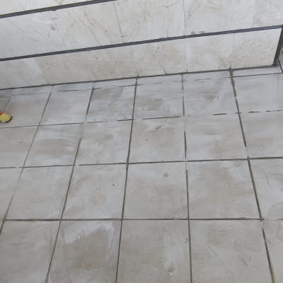 רצפה מרוצפת עם סימני לכלוך ונעליים של עובד