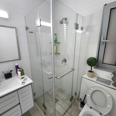 מקלחון זכוכית עם מדפים ומוצרים