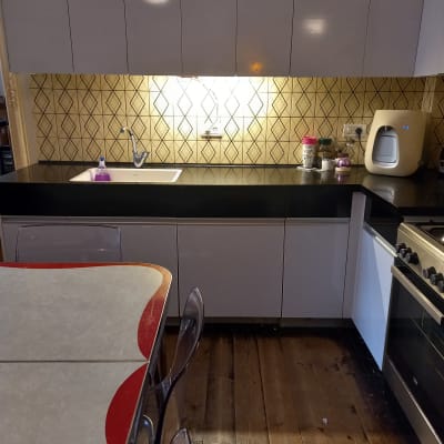 מטבח עם ארונות לבנים, כיור וברז, מכשירי חשמל על השיש