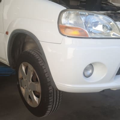 רכב לבן מורם על ליפט במוסך