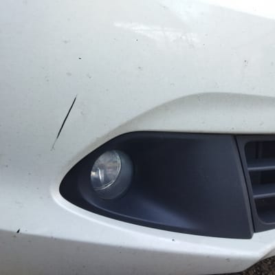 פנס ערפל קדמי ושריטות על פגוש רכב לבן