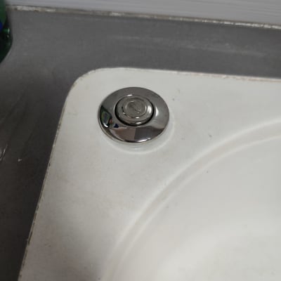 כפתור כרום עגול על כיור לבן