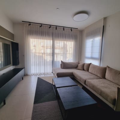 וילונות לבנים שקופים תלויים על חלון גדול בסלון