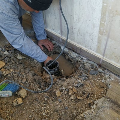 אדם עובד על איטום חור ברצפה עם צינור