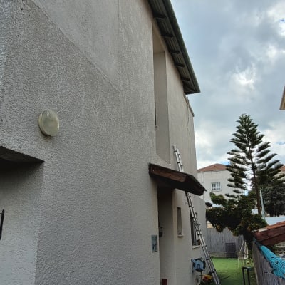 סולם מונח על קיר בית עם ציוד עבודה בחצר