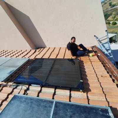 אדם יושב ליד דוד שמש על גג רעפים