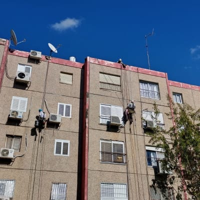 עובדים על חבלים מבצעים איטום קירות חיצוניים