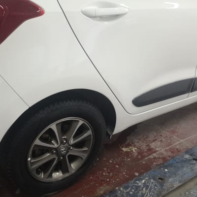 חלק אחורי של רכב לבן עם פגוש וצמיג