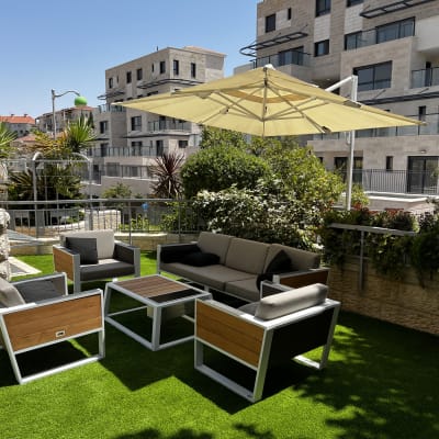 צמחים ירוקים ופרחים על מרפסת עם דשא סינתטי