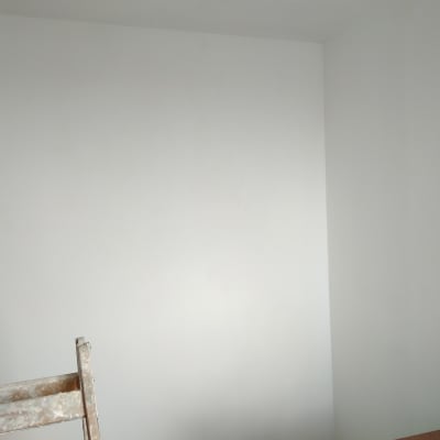 קיר צבוע בלבן עם סולם מוכתם בצבע
