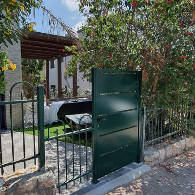 שער וגדר מתכת ירוקים בכניסה לחצר