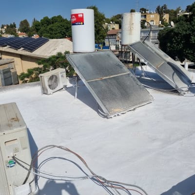 גג אטום בלבן עם קולטי שמש ומזגנים