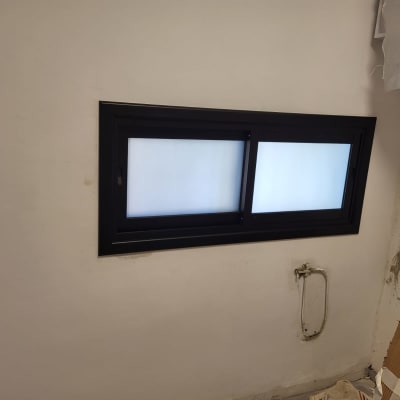 חלון אלומיניום עם מסגרת כהה על קיר לבן