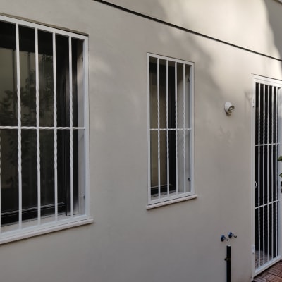 חלונות ודלת עם סורגים לבנים על קיר חיצוני