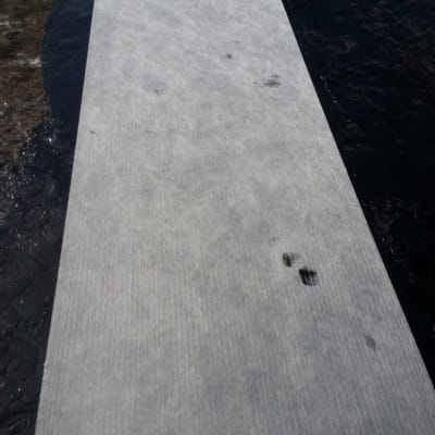 יריעת איטום נפרשת על גג כהה