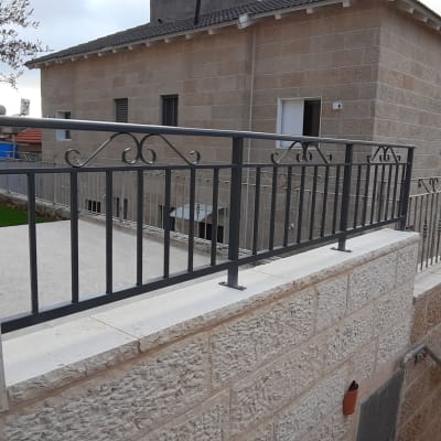 מעקה מתכת מעוצב על קיר אבן חיצוני