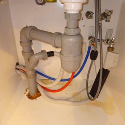 צנרת פלסטיק מתחת לכיור עם חיבורים וצינורות צבעוניים