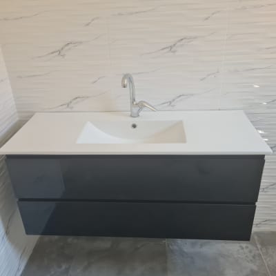 כיור חדש עם ארון שחור על קיר מרוצף