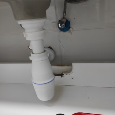 צינור מתחת לכיור עם מפתח צינורות אדום