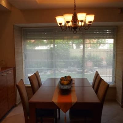 A dining room with a sheer curtain covering a large window.