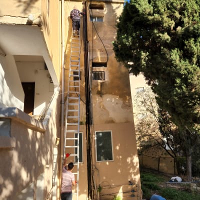 אדם על סולם ליד צינורות בניין