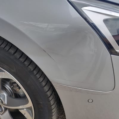 שריטות על פגוש רכב אפור ליד גלגל קדמי