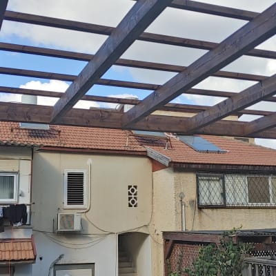 פרגולה מעץ עם קורות עץ חומות בגינה
