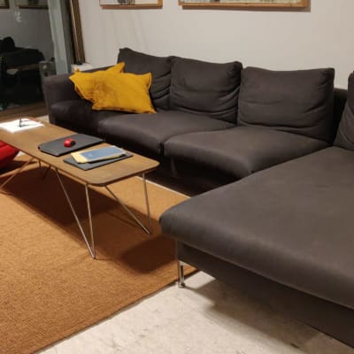 ספה אפורה עם כרית צהובה ושולחן קטן