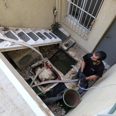 אדם עם כפפות מחזיק צינור ליד בור פתוח