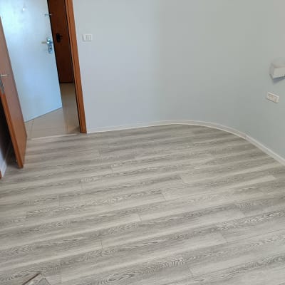 רצפת פרקט עץ אפור בחדר עם דלת פתוחה