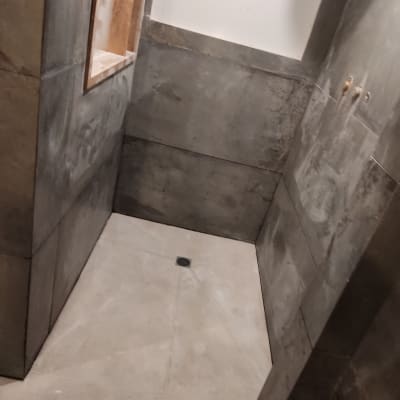 חדר רחצה בשיפוץ עם קירות בטון ורצפת אריחים