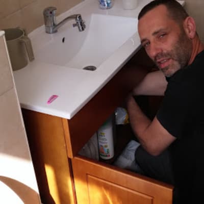 אדם מתקן ארון מתחת לכיור בחדר אמבטיה