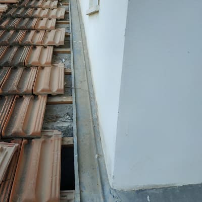 רעפים על גג ליד קיר לבן עם פח