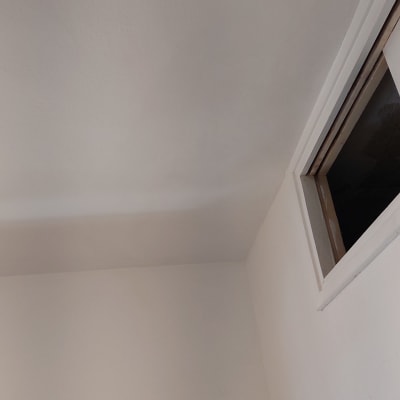 קיר ותקרה צבועים בלבן עם חלון קטן