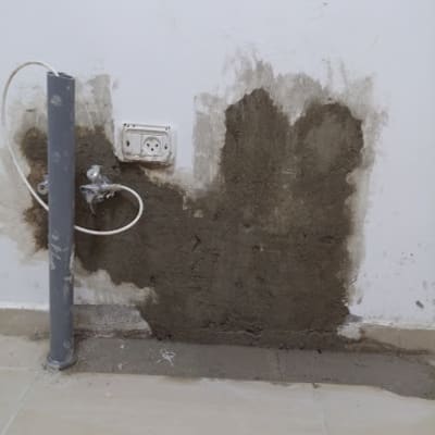 צינור מים ליד קיר עם טיח רטוב