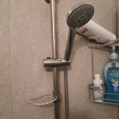 ראש מקלחת מתכוונן על מוט מתכת בחדר אמבטיה