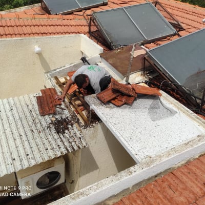 אדם מתקן גג רעפים עם לוחות עץ וקרמיקה