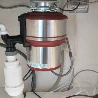 מכשיר טוחן אשפה מתחת לכיור עם צינורות חיבור